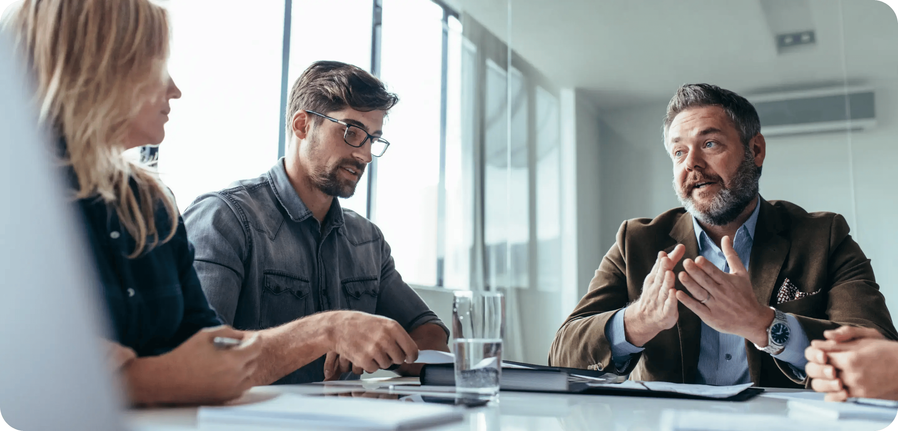 A picture of a boardroom meeting, featuring a young husband and wife, talking to their finance specialist about a loan.